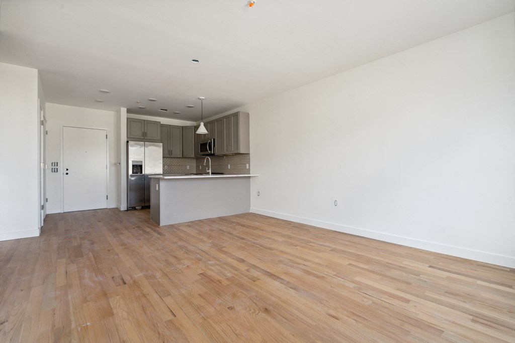 an empty living room and kitchen with wood flooring