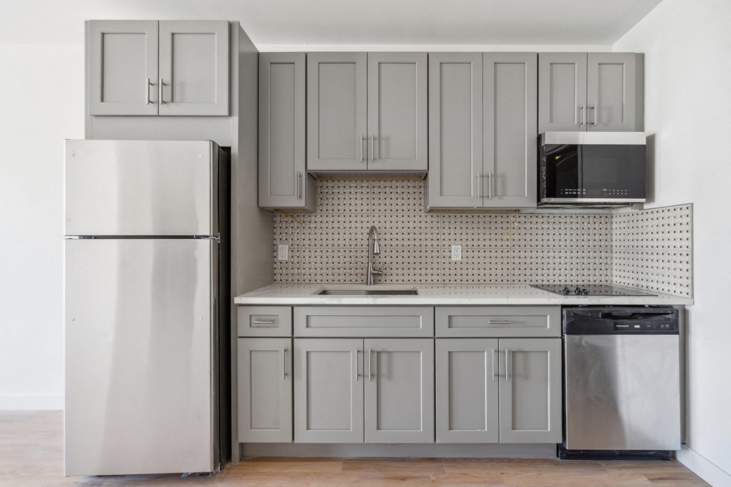 an empty kitchen with white cabinets and a refrigerator