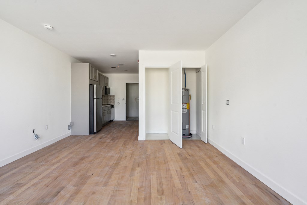 a renovated living room and kitchen with wood floors and white walls