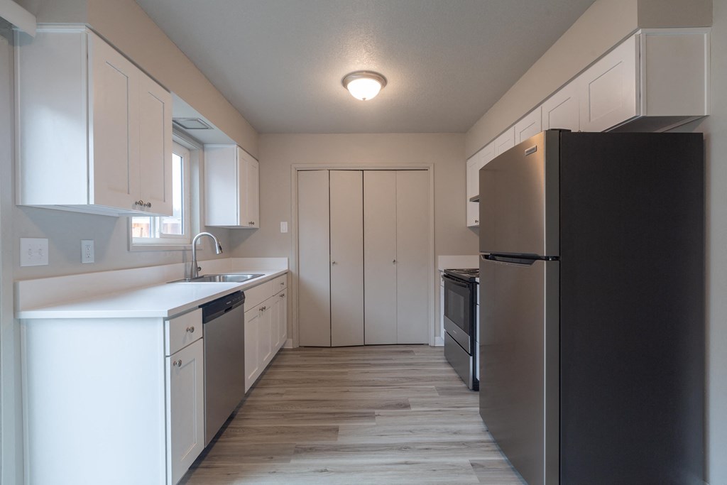 a kitchen with white cabinets and a black refrigerator