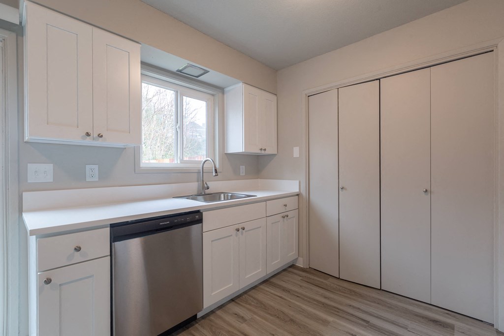 a kitchen with white cabinets and a stainless steel dishwasher