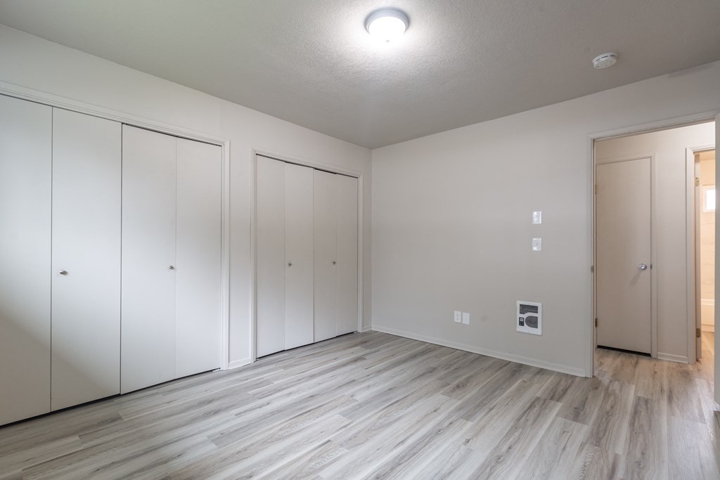 a bedroom with white walls and a wooden floor
