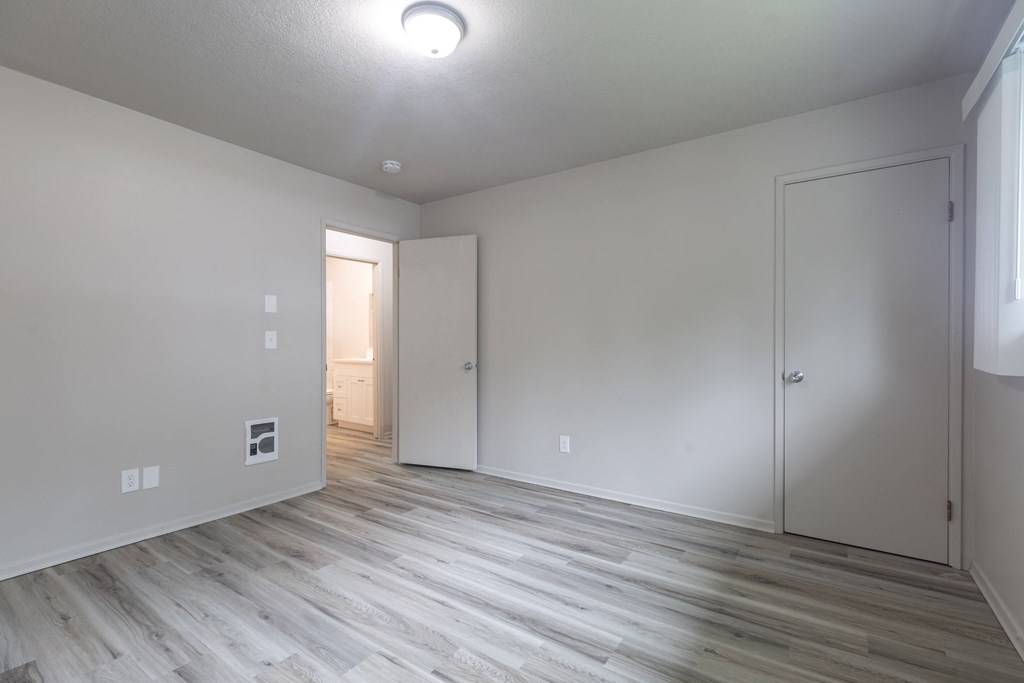 a bedroom with hardwood floors and white walls