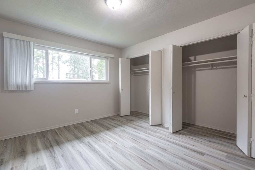 an empty bedroom with a large window and two closets
