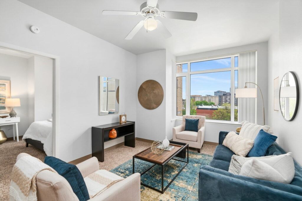 A living room with a white ceiling fan and a large window. at Pacific Tower Apartments, Portland, OR