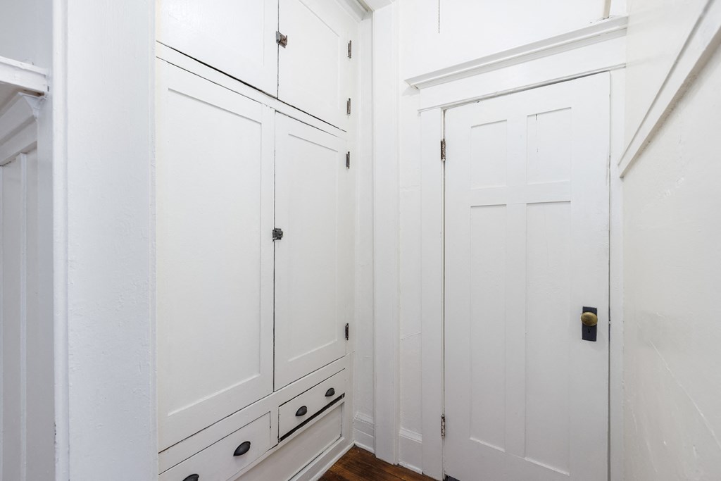 a closet in a bedroom with white walls and a wooden floor