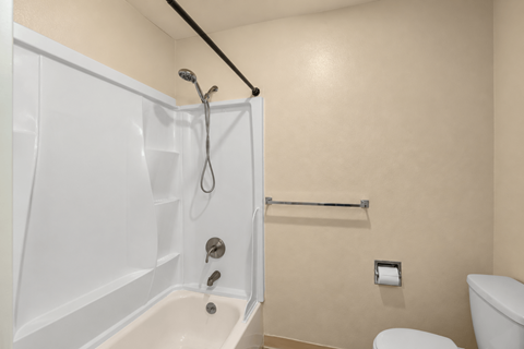 A white bathtub with a shower head and a towel bar.