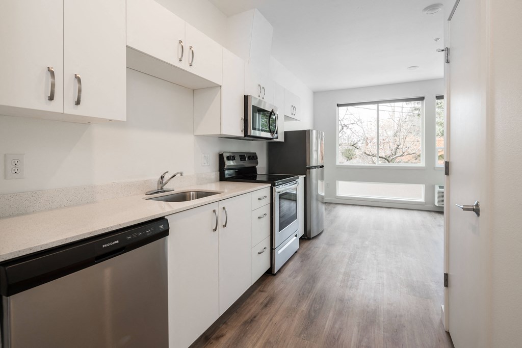 a kitchen with white cabinets and stainless steel appliances and a window