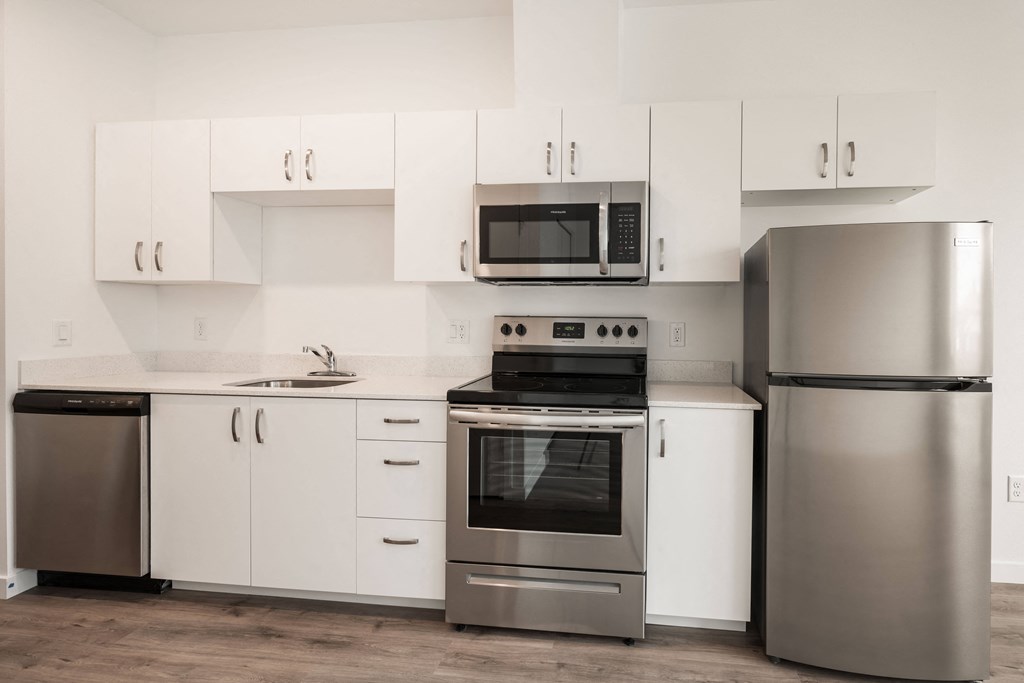 a white kitchen with stainless steel appliances and white cabinets