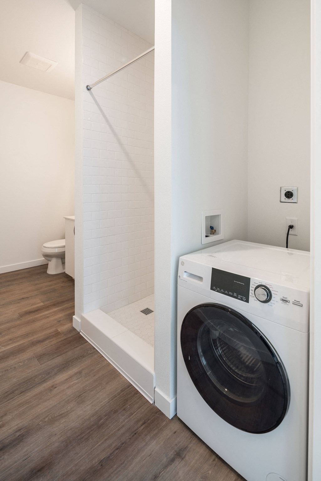a white washer and dryer in a room with a shower and a toilet