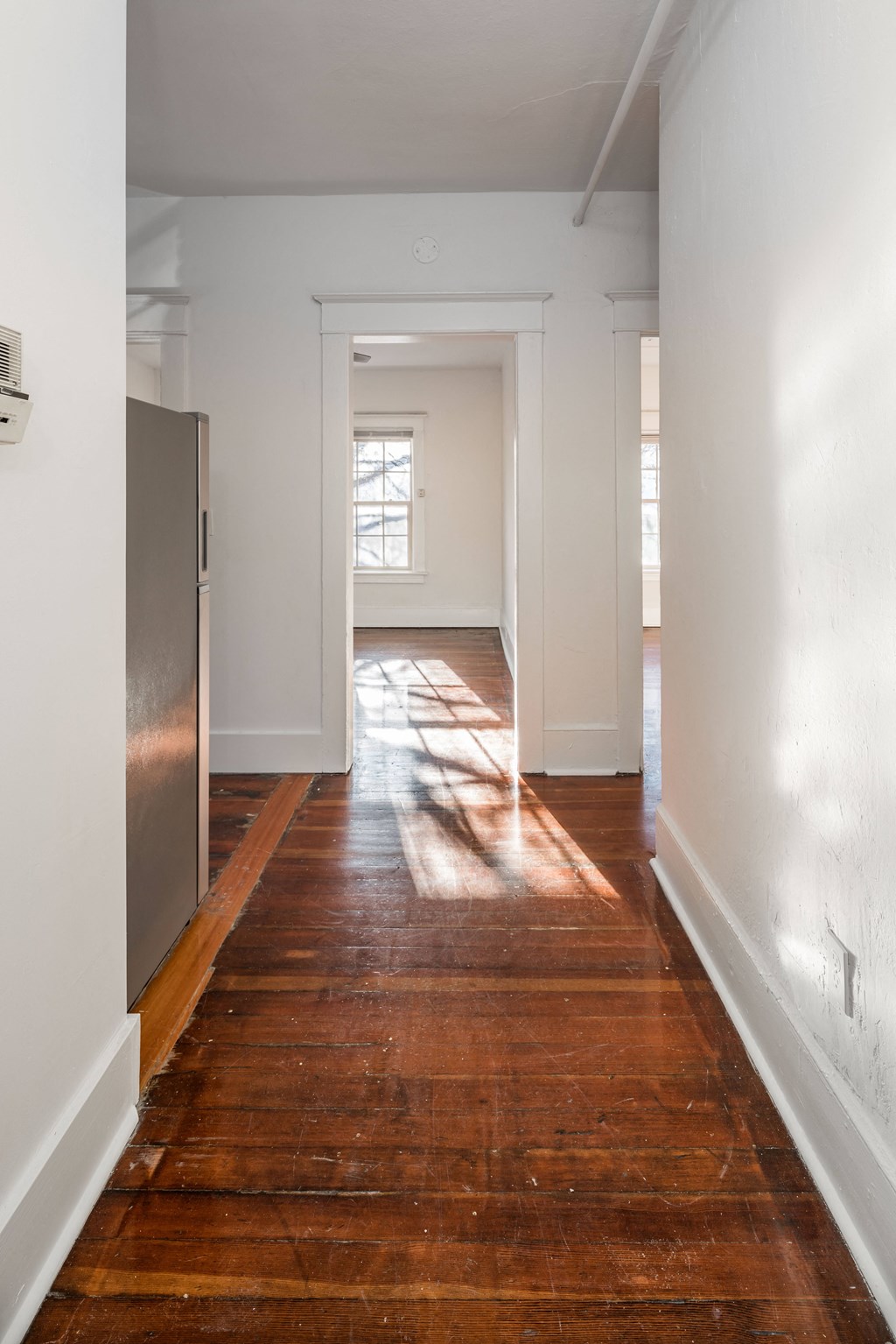 a living room with wood floors and white walls and a window