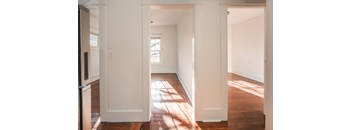 an empty living room with white walls and wood floors