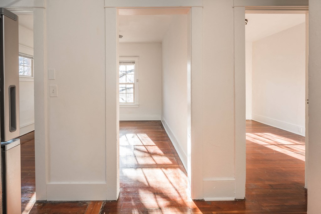 an empty living room with white walls and wood floors