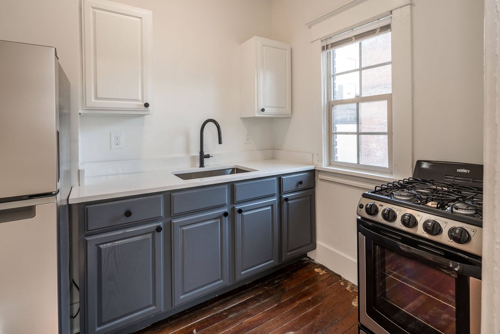 a kitchen with blue cabinets and a stove and a window