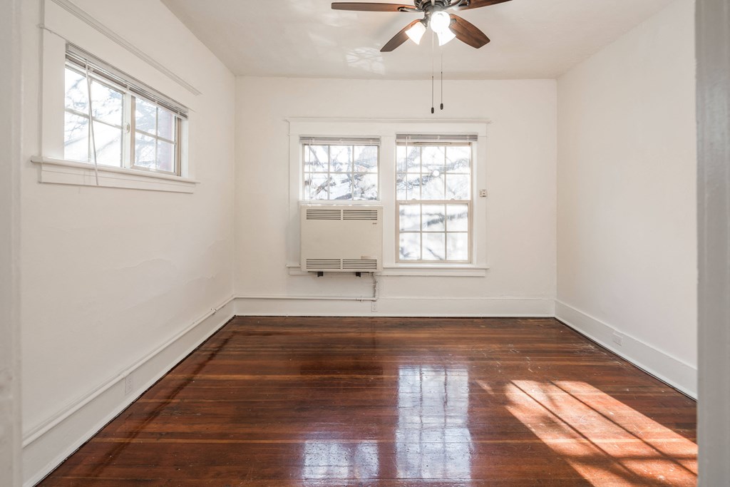 an empty room with wood floors and a ceiling fan