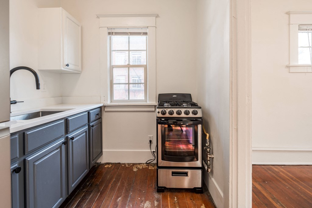 a kitchen with a stove and blue cabinets and a window