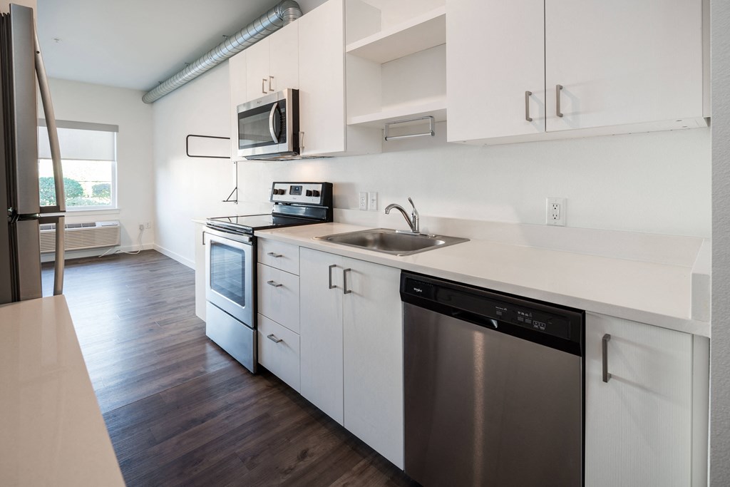 an empty kitchen with white cabinets and stainless steel appliances