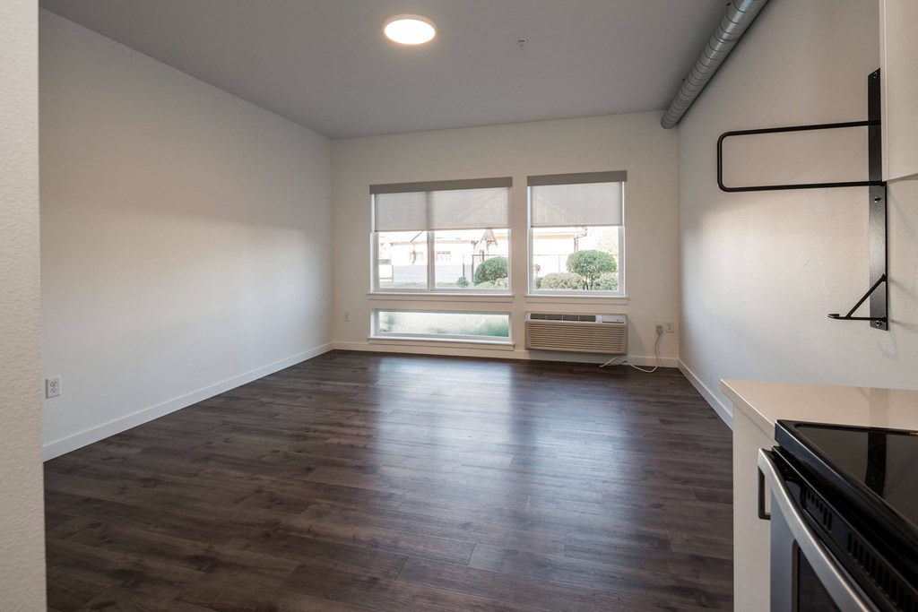 an empty living room with a window and a kitchen