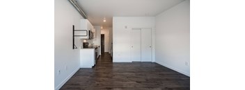 a kitchen and living room with white walls and wood flooring