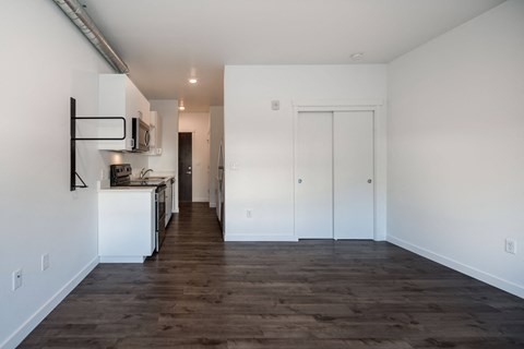 a kitchen and living room with white walls and wood flooring