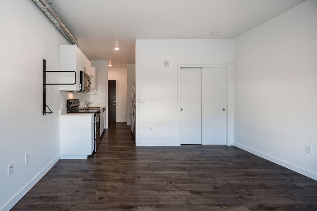 a kitchen and living room with white walls and wood flooring