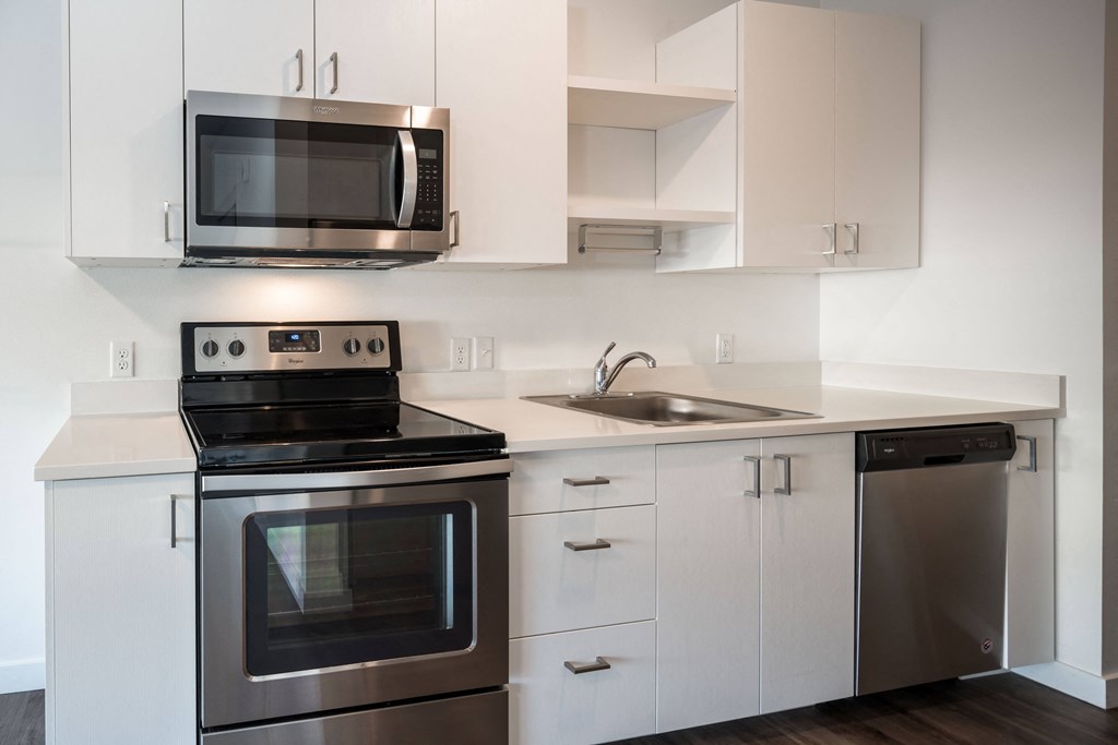 an empty kitchen with stainless steel appliances and white cabinets