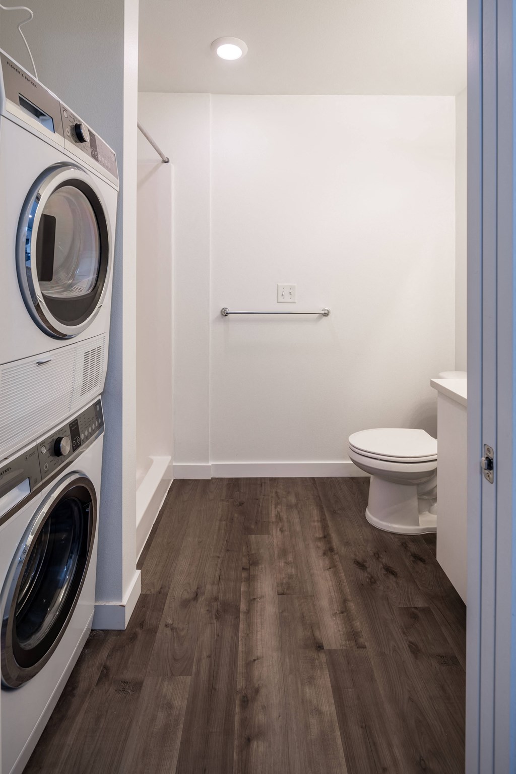 a bathroom with a washer and a toilet and a dryer in it