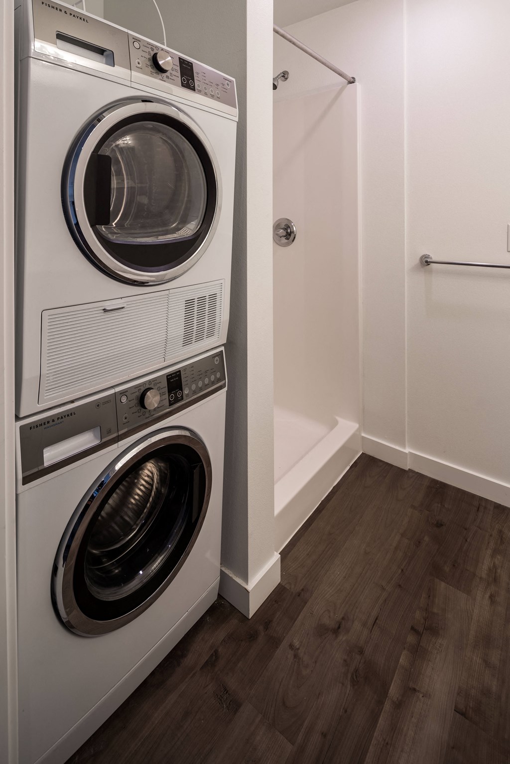 a washer and dryer in a small laundry room with a shower