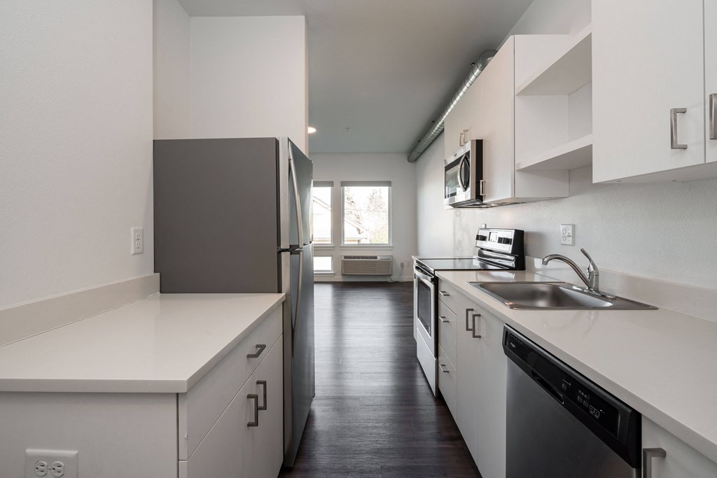 an empty kitchen with white counters and a stainless steel refrigerator