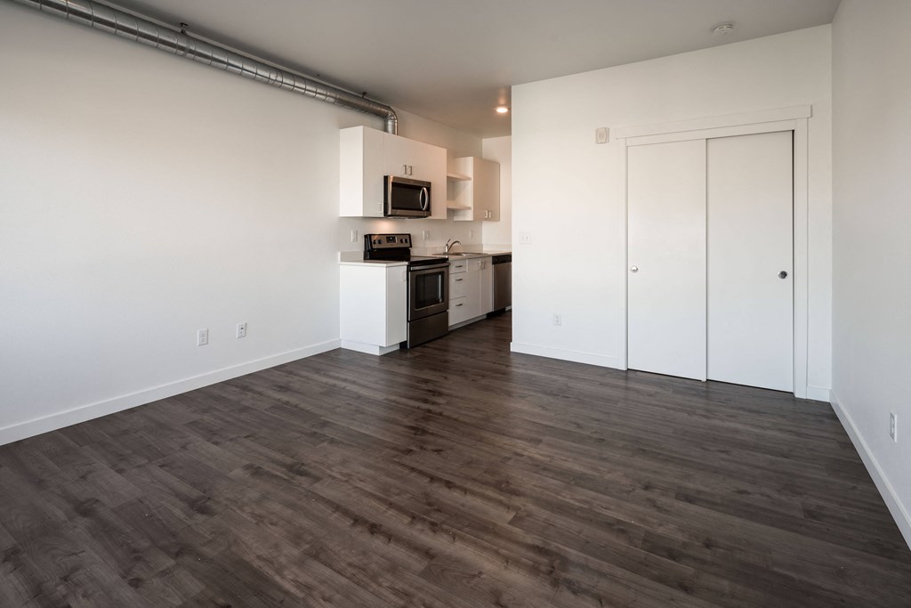 a kitchen and living room with white walls and wood floors