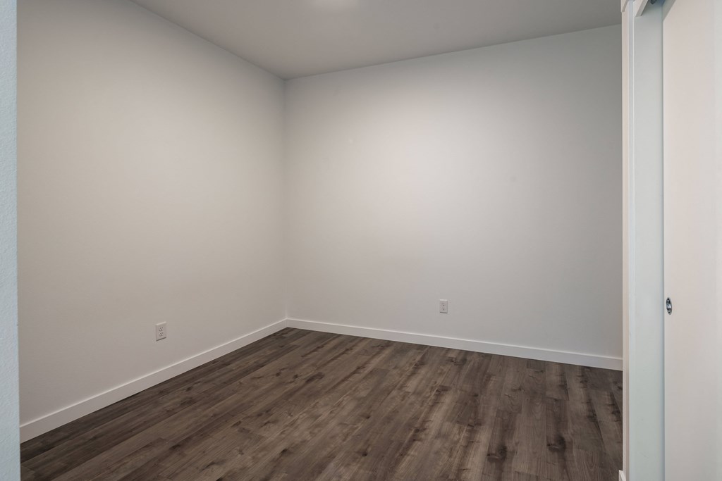 an empty room with wooden floors and white walls