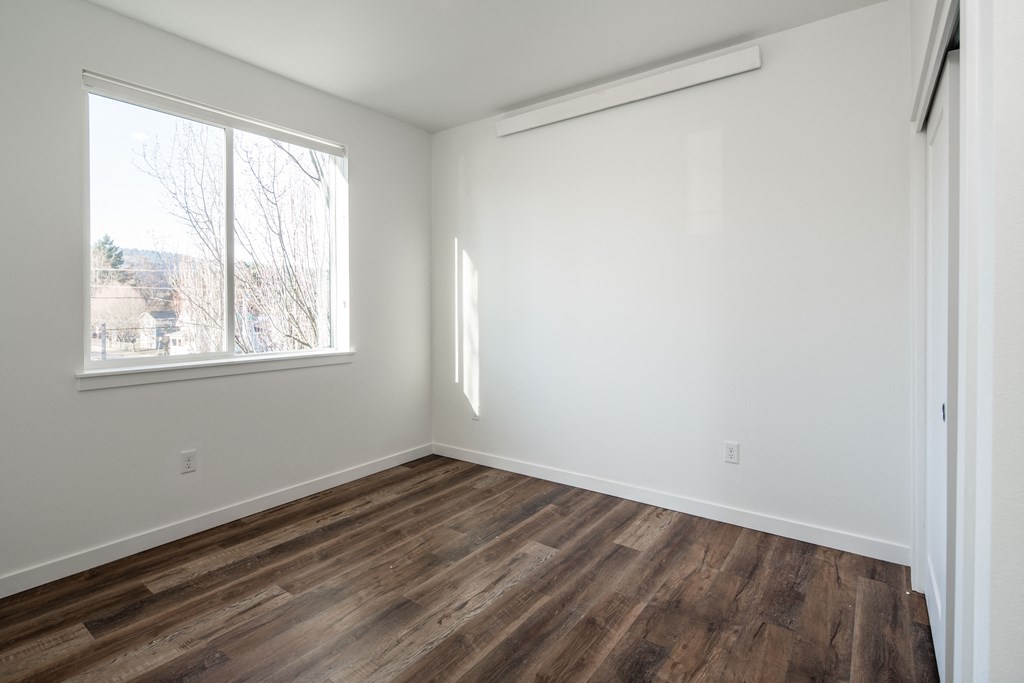 an empty room with wood floors and a window