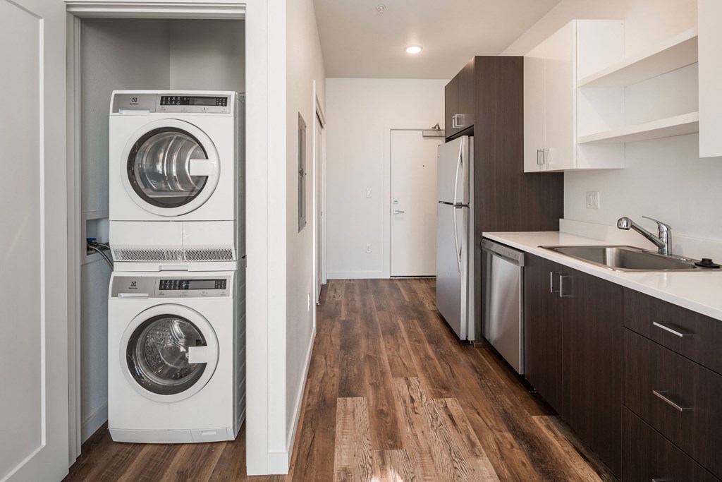 a washer and dryer in a kitchen with a sink and a refrigerator