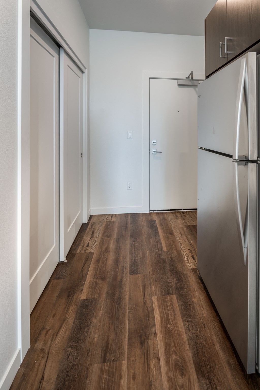 a kitchen and living room with a refrigerator and wooden floors
