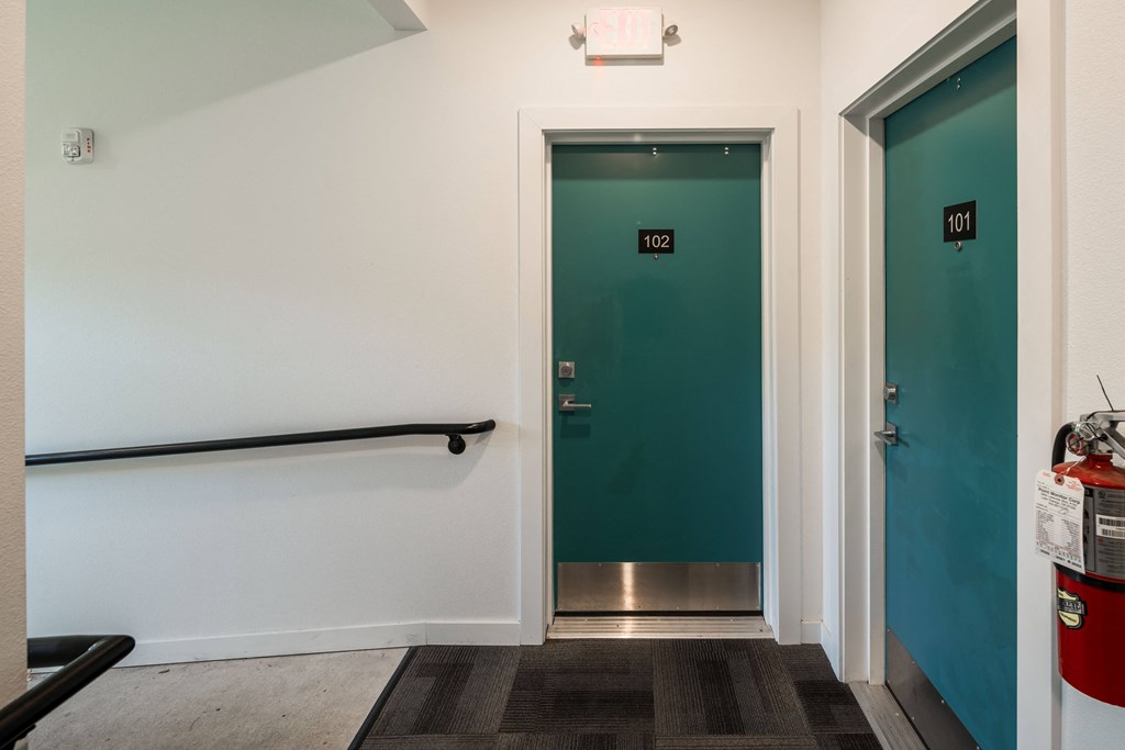 a hallway with two green doors and a white wall