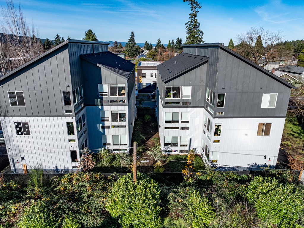a view from above of three buildings with trees and bushes