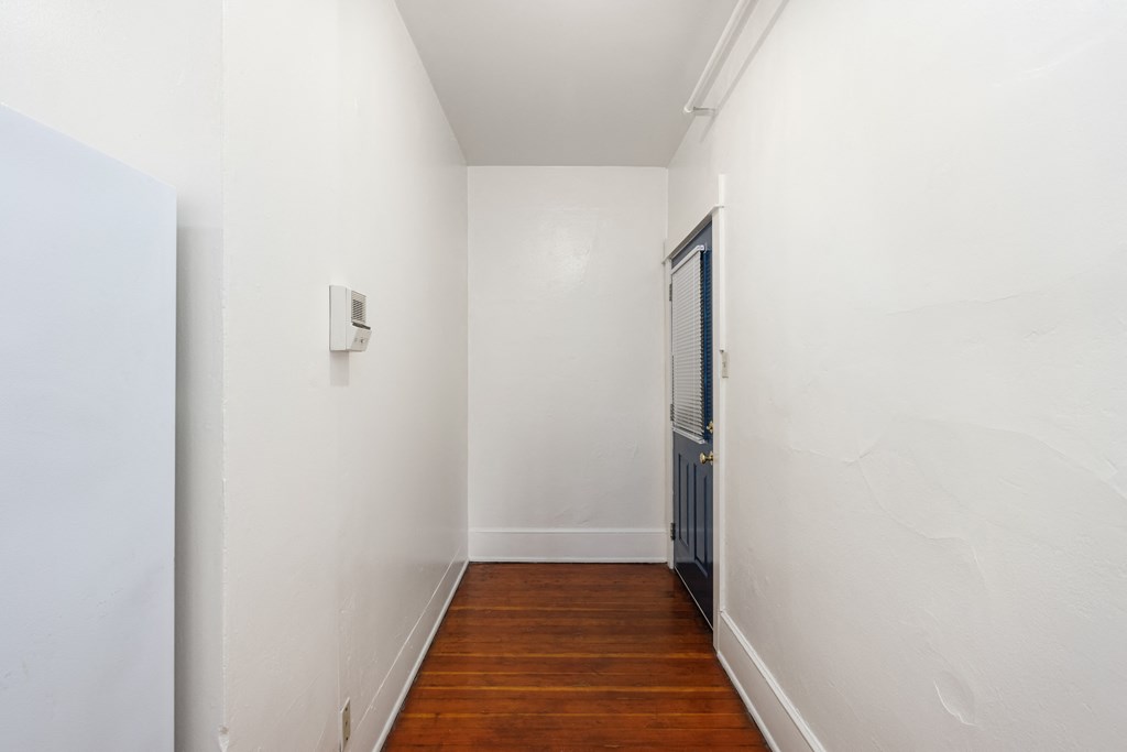 a corridor with white walls and a wooden floor