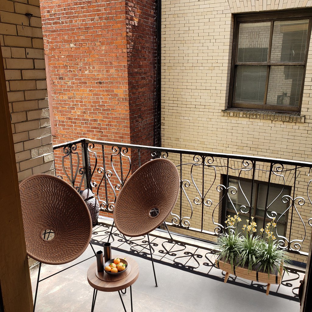a balcony with two chairs and plants and a brick building