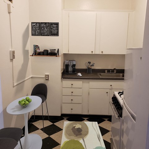 a small kitchen with white cabinets and a black and white checkered floor