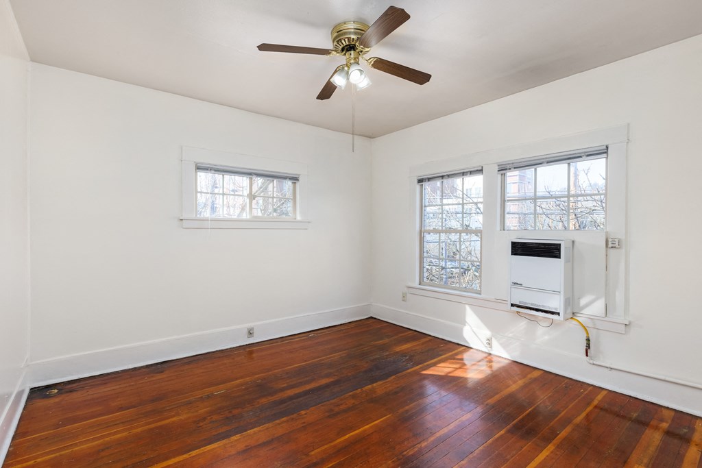 a bedroom with a ceiling fan and three windows