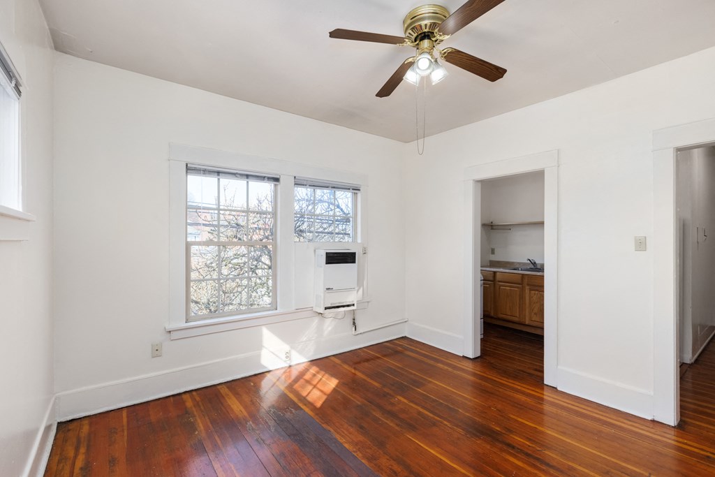 a bedroom with a ceiling fan and two windows