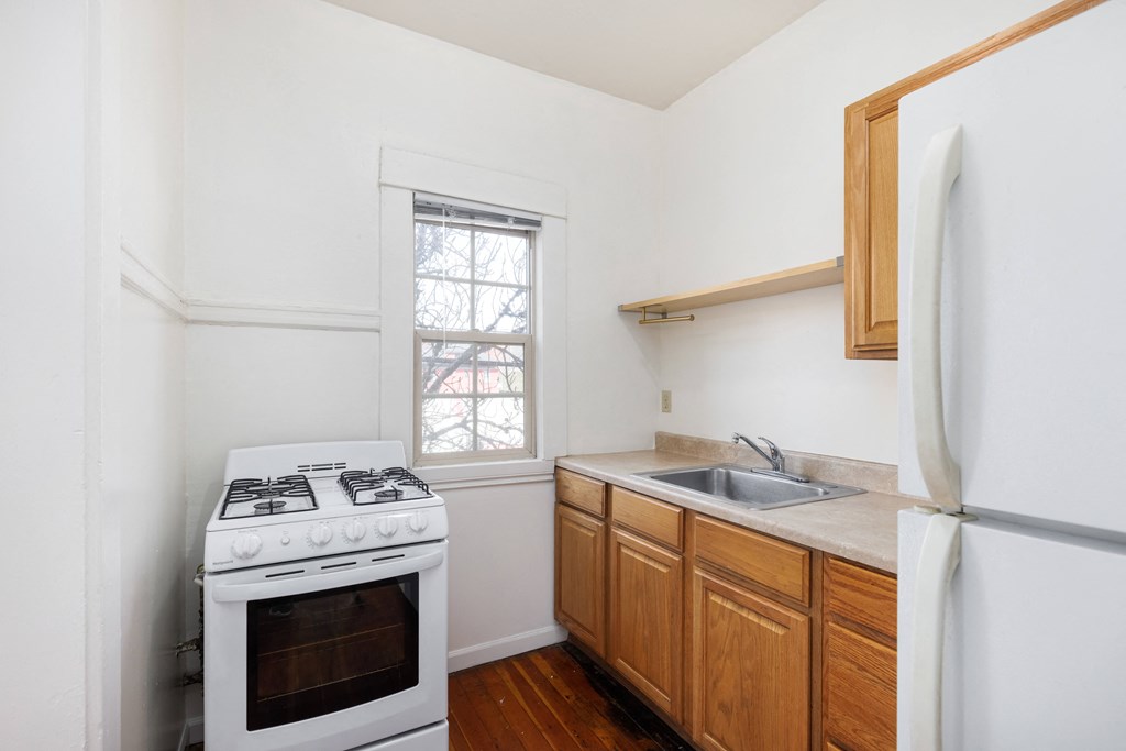 a kitchen with white walls and wooden cabinets