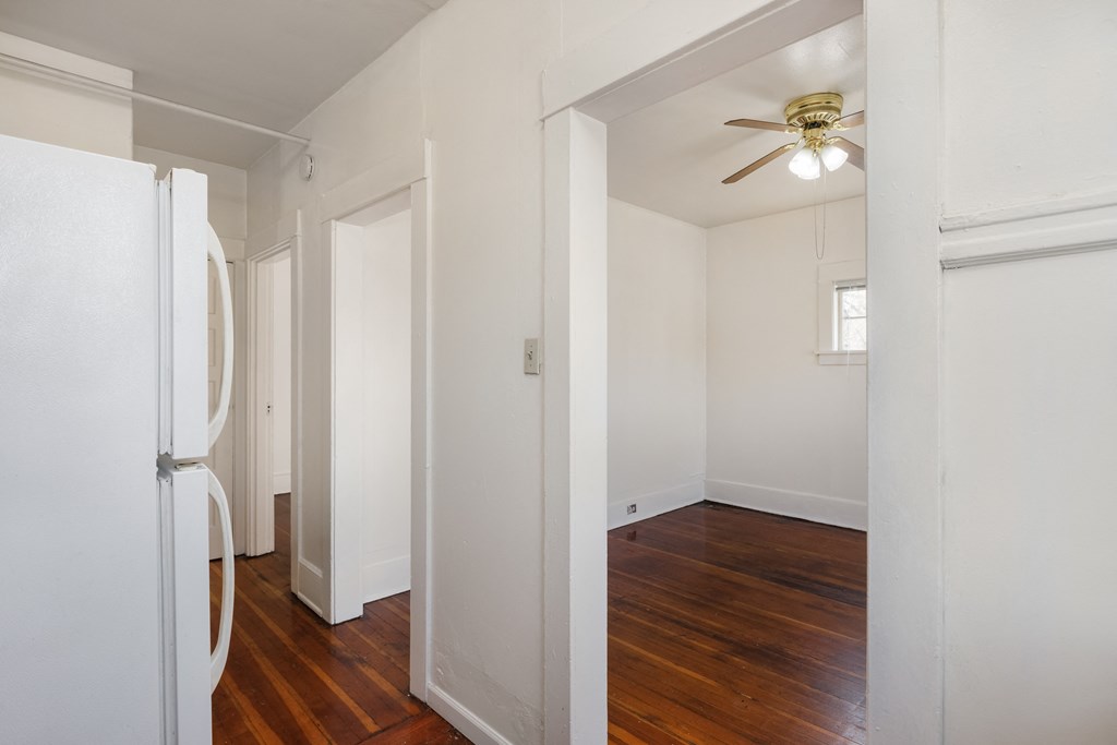 a bedroom with white walls and a ceiling fan