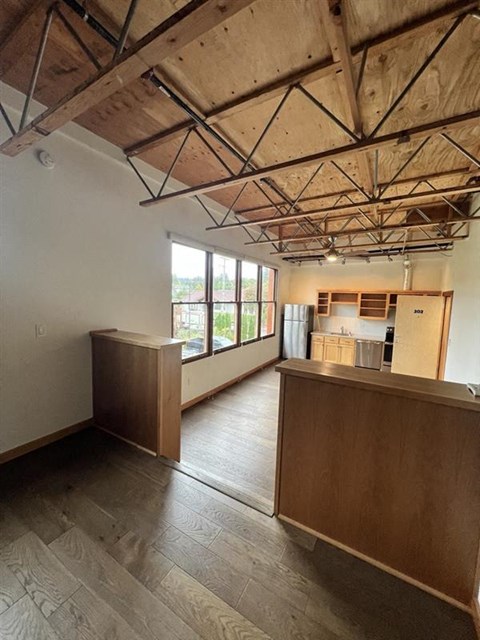 an empty living room and kitchen with wood floors
