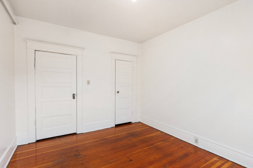 a bedroom with two doors and a hardwood floor