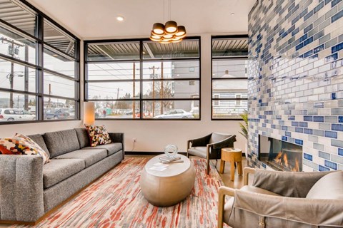 A living room with a grey couch, a brown coffee table, and a fireplace with a blue and white tiled wall.