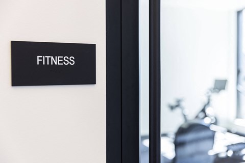 a fitness gym sign on a wall next to a mirror at Analog PDX Apartments, Portland