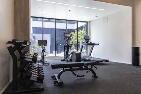 a gym with treadmills and other exercise equipment in front of a window at Analog PDX Apartments, Oregon 97227