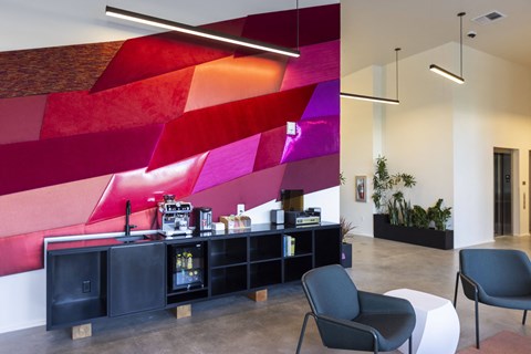 a lobby with a counter and chairs and a colorful wall at Analog PDX Apartments, Portland, OR
