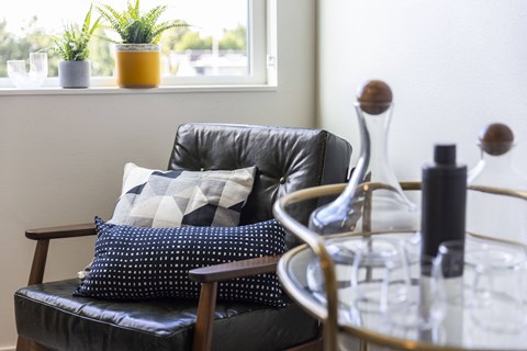 a living room with a black leather couch and pillows on it at Analog PDX Apartments, Portland, OR 97227